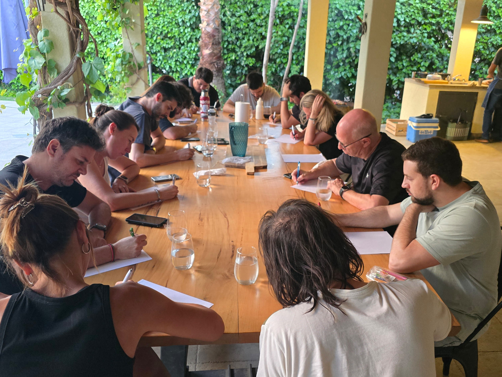 Equipo escribiendo alrededor de una mesa larga durante una consigna
